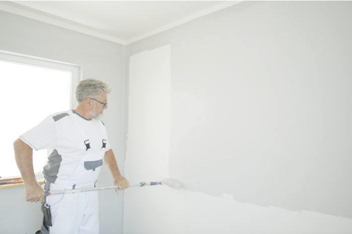 Ein Malermeister streicht eine Wand in großen Bahnen.