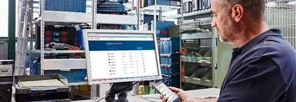 Person am Computer mit Smartphone