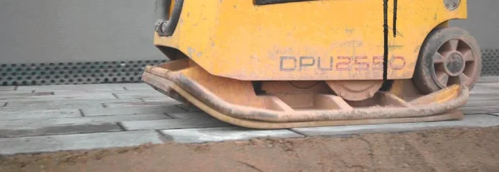 Eine Rüttelplatte verfestigt Pflastersteine.