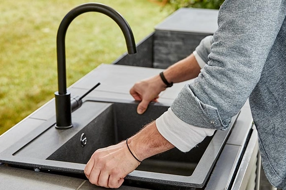 Person hebt Spüle in Außenküche ein