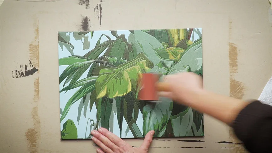 Person klebt Dschungelmotiv auf Leinwand