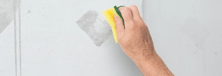 Person reinigt Wand mit Schwamm