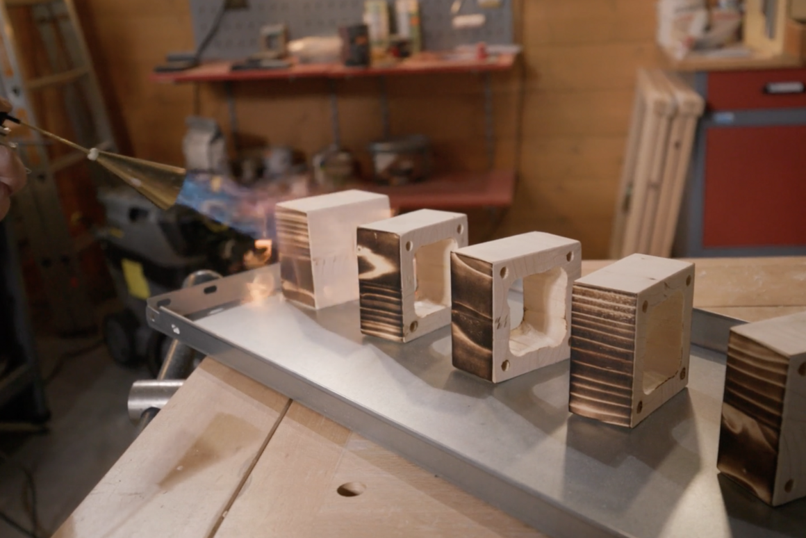 Holzklötze werden mit einem Gasbrenner abgeflämmt.