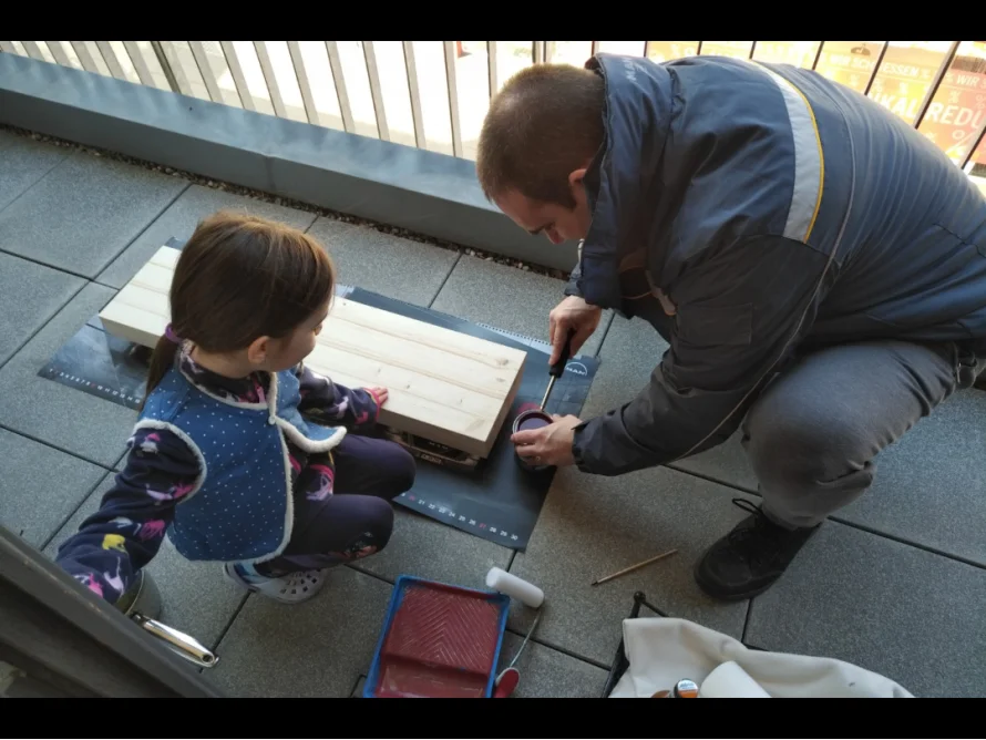 Person und Kind beim Lasieren von Holz