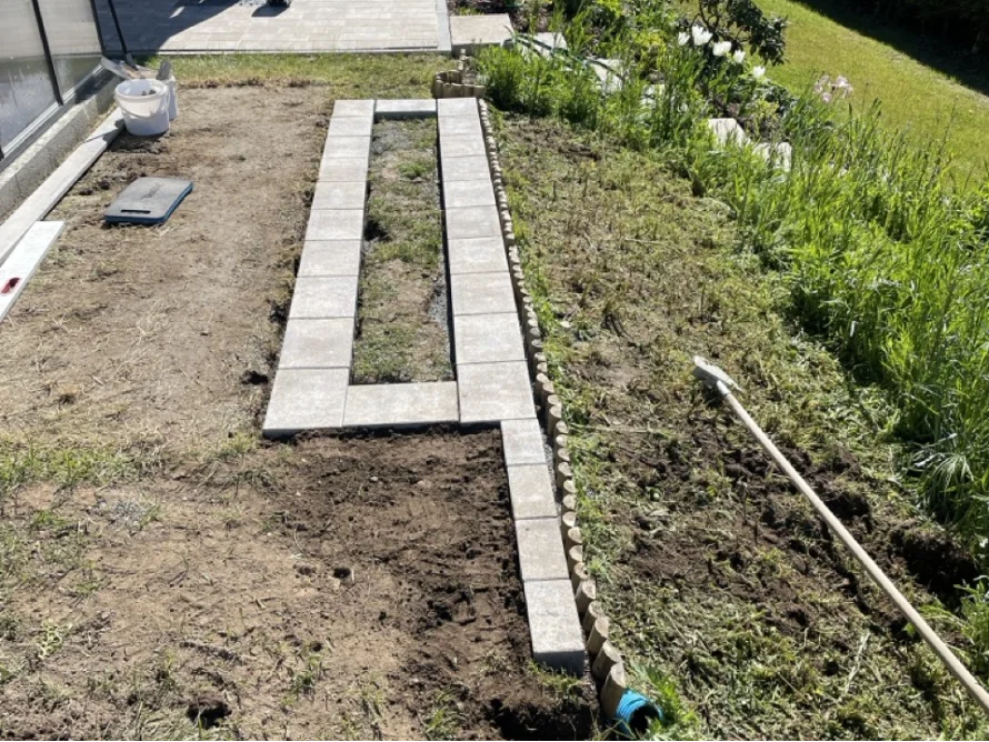 Pflasterarbeiten im Garten mit Harke