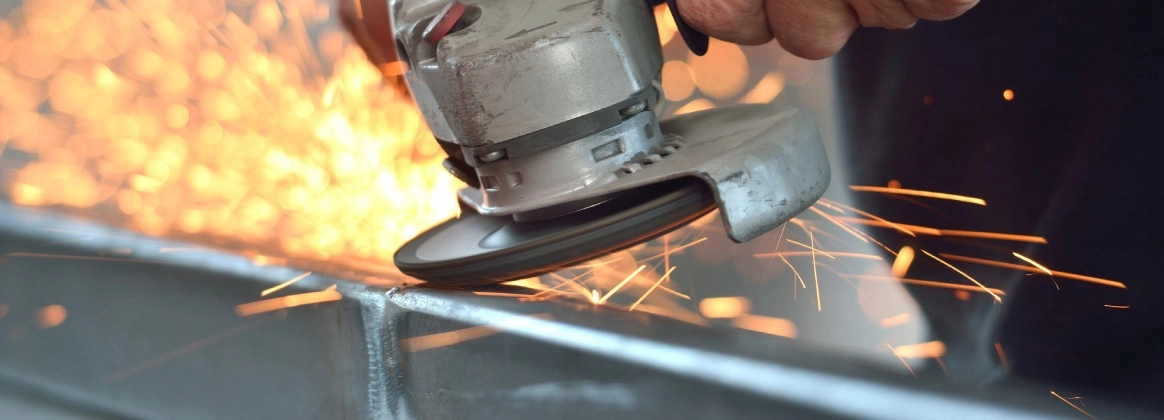 Nahaufnahme eines Winkelschleifers, der Metall mit Funkenflug bearbeitet.