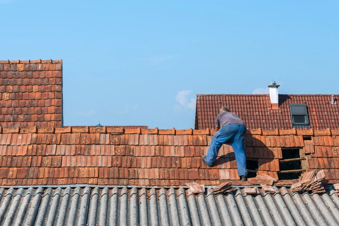 Person repariert ein Ziegeldach