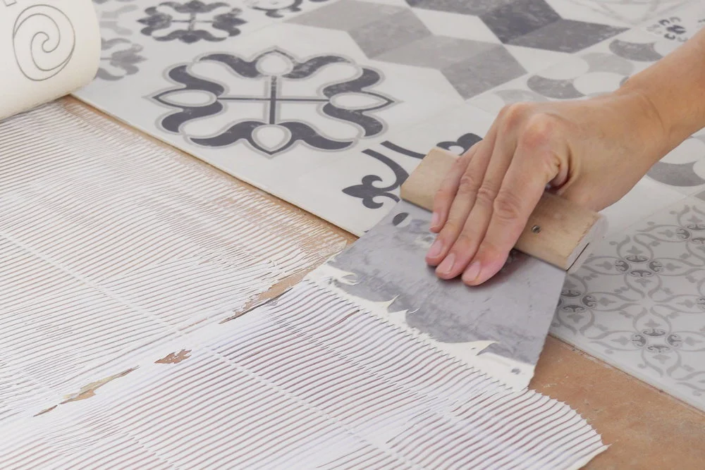 Hand verteilt Fliesenkleber mit Spachtel