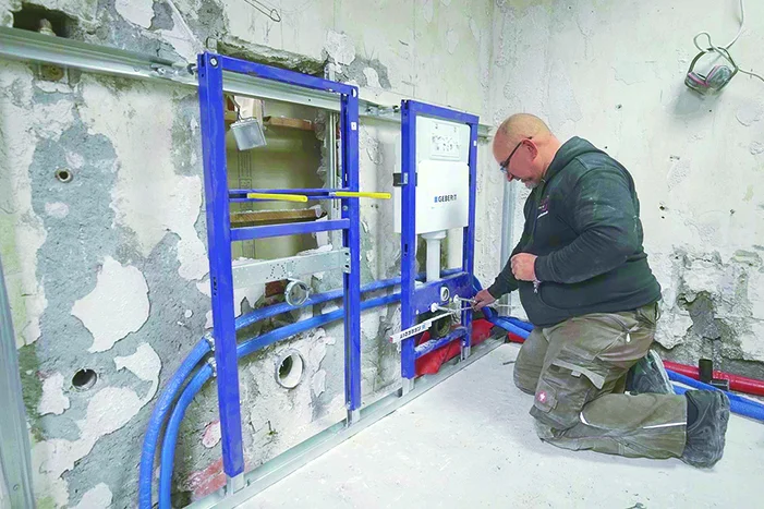 Person montiert Toilettenspülkasten an Wand.