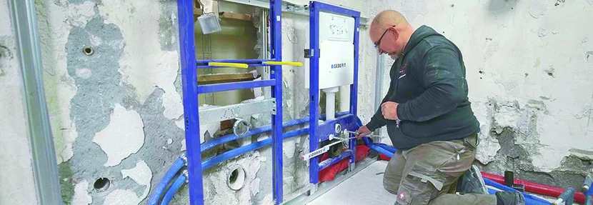 Person montiert Toilettenspülkasten an Wand.