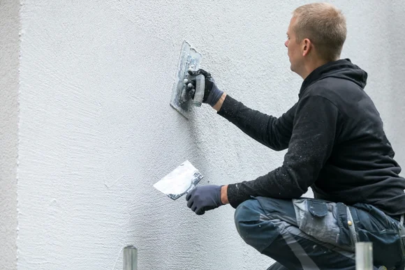 Person verputzt Wand mit Kelle