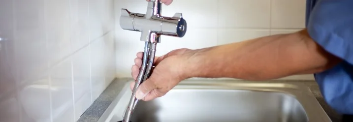 Person montiert eine Wasserarmatur.