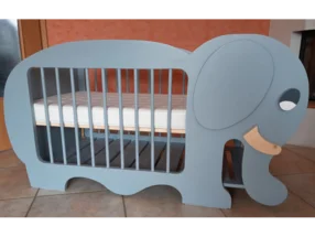 Ein blaugraues Babybett in Form eines Elefanten.