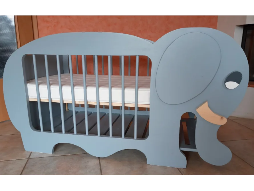 Ein blaugraues Babybett in Form eines Elefanten.