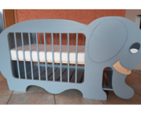 Ein blaugraues Babybett in Form eines Elefanten.