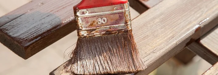 Person streicht Holzbank mit Pinsel