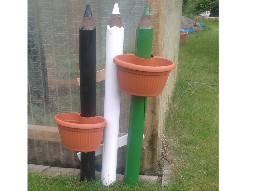 Drei bunte Pfähle mit Blumentöpfen