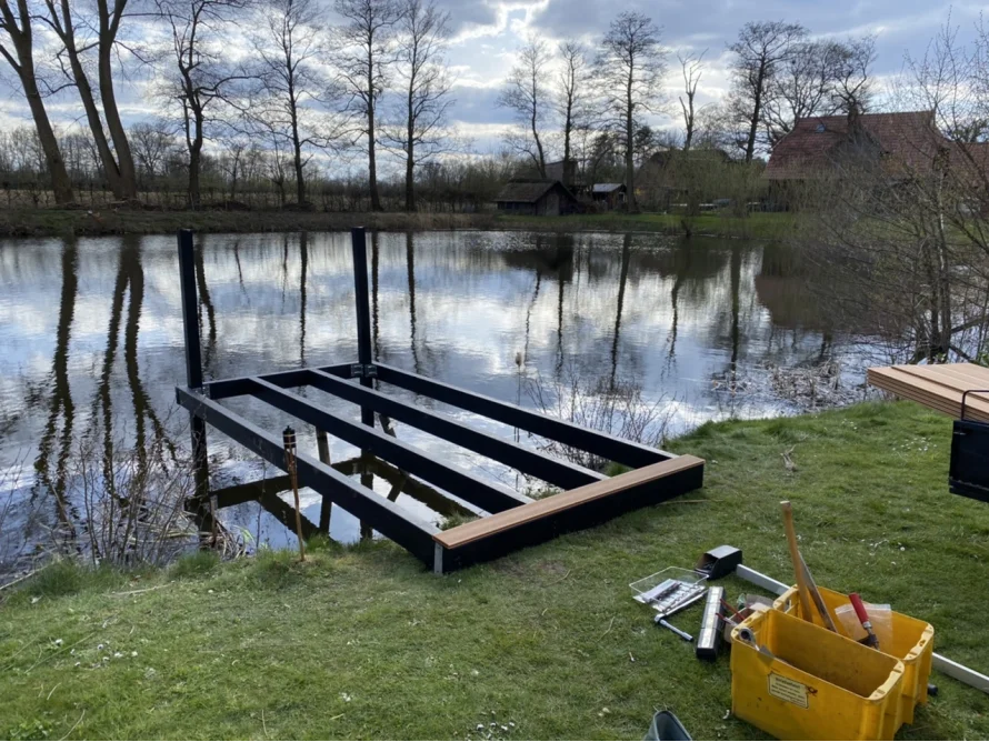 Holzsteg am Ufer eines Teichs im Bau