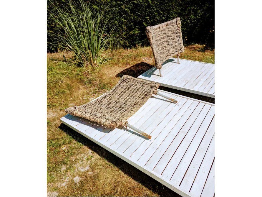 Zwei geflochtene Liegestühle auf Holzterrasse