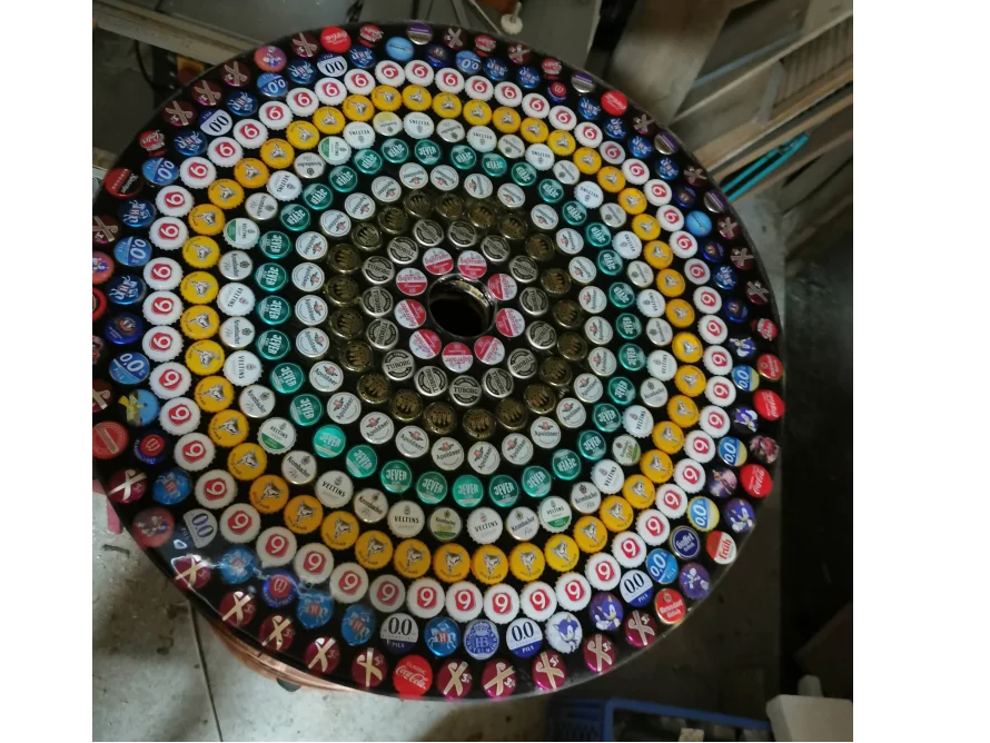 Ein runder Tisch, der mit Kronkorken in verschiedenen Farben verziert ist.