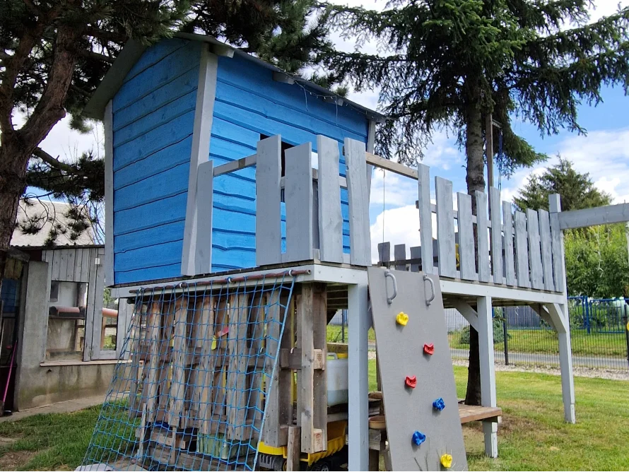 Blaues Spielhaus aus Holz mit Kletterwand
