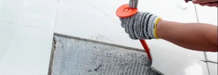 Hand mit Hammer und Meißel entfernt Fliese