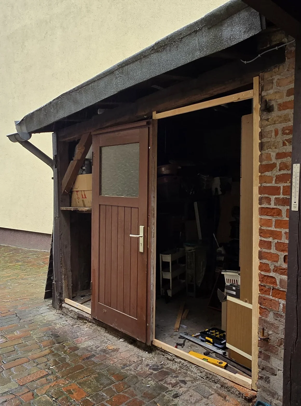 Holztür wird in einen Schuppen eingebaut, davor liegt eine Wasserwaage.