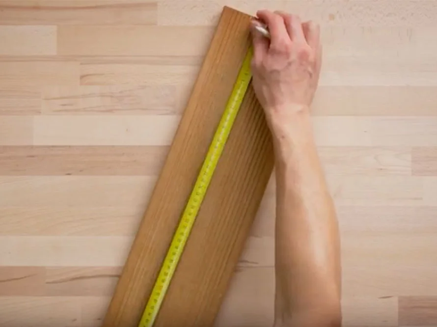 Person misst Holzbrett mit Zollstock ab