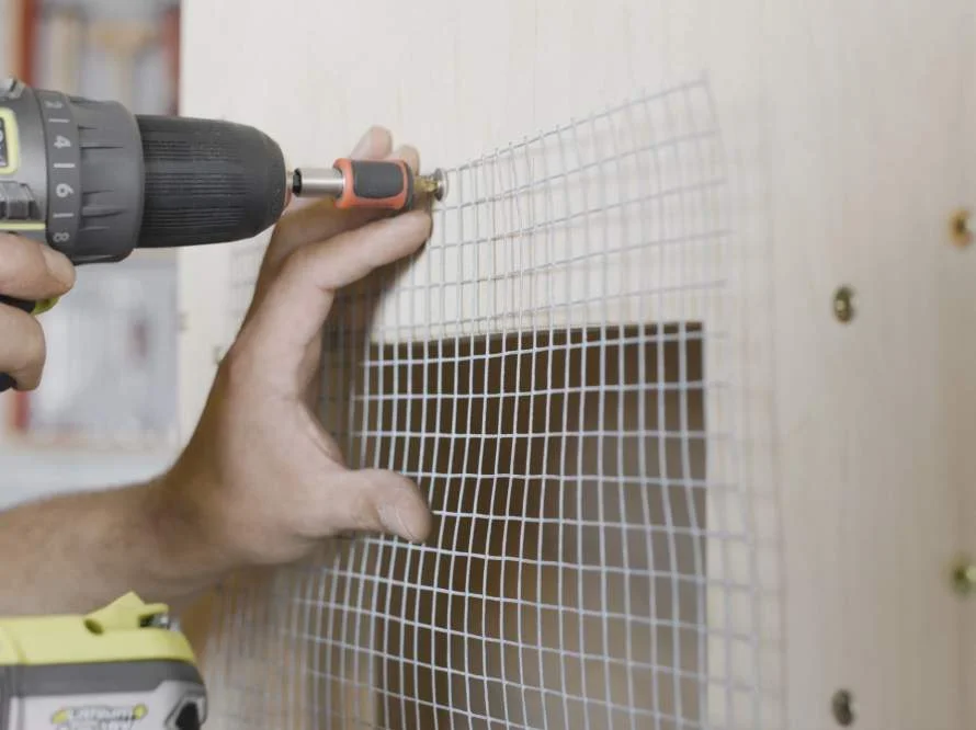 Person befestigt Drahtgitter mit Akkuschrauber