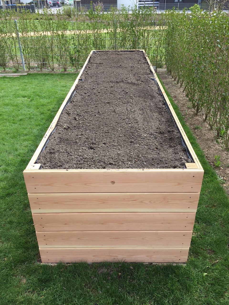 Hochbeet aus Holz mit Erde gefüllt