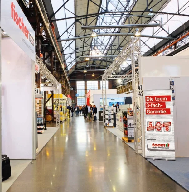 Messehalle mit Messeständen und Personen