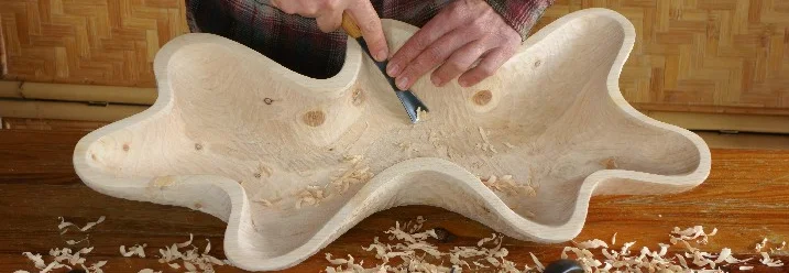 Person schnitzt Schale mit Werkzeug