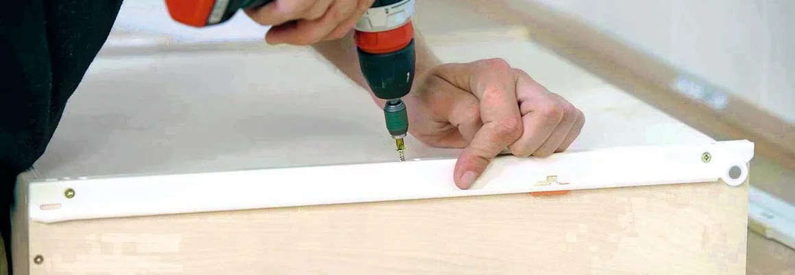 Person montiert Schubladenschiene mit Akkuschrauber.