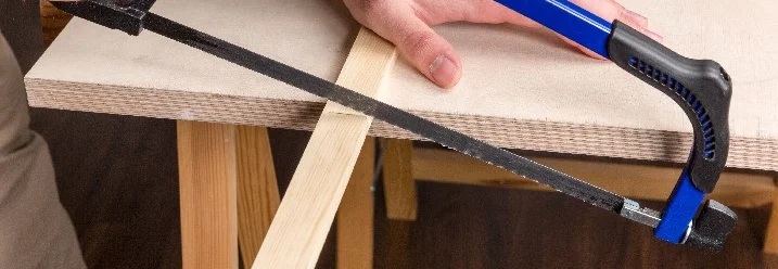 Person sägt Holz mit Bügelsäge.