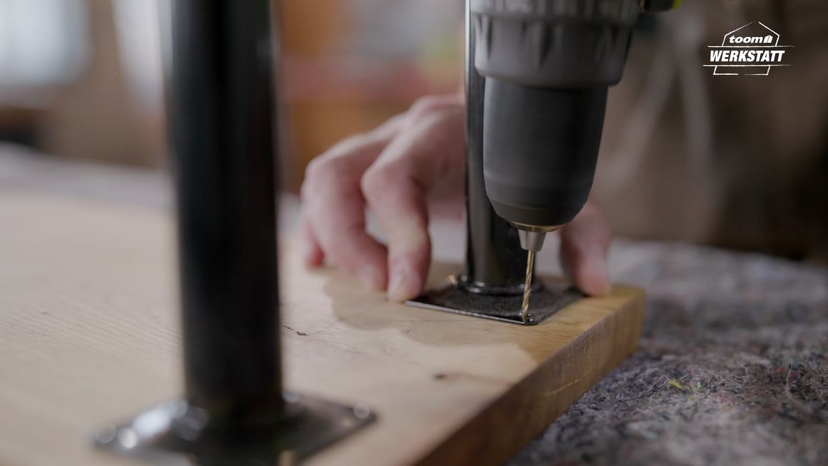 Person verschraubt Holz mit Metallplatte