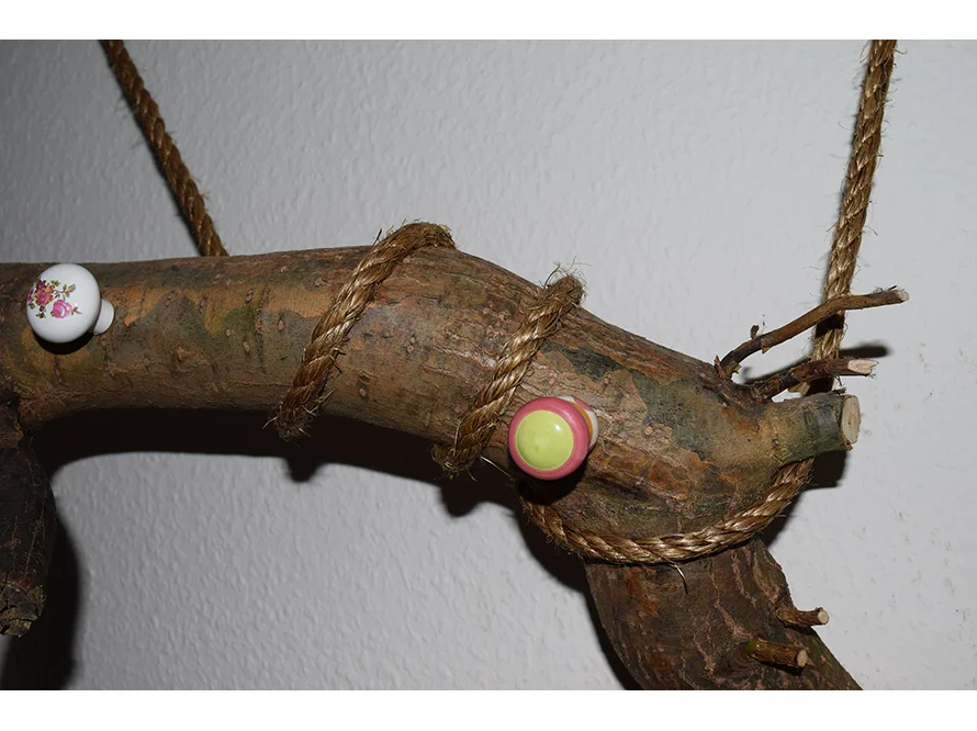 Ast mit Seil und Knäufen als Kleiderhaken