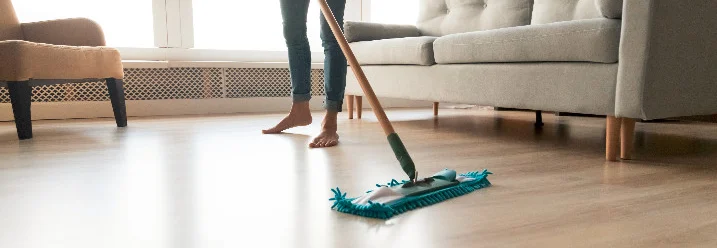 Person wischt Holzboden mit Wischmopp