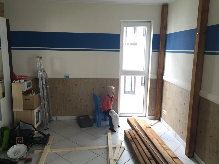 Kind in einem Zimmer mit Holzlatten auf dem Boden