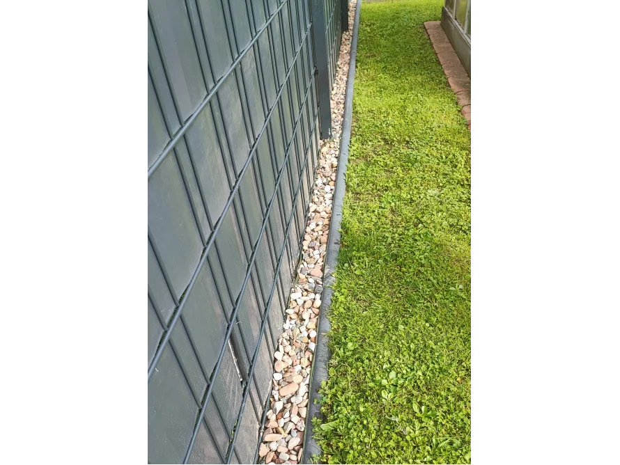 Kiesstreifen zwischen Zaun und Rasen