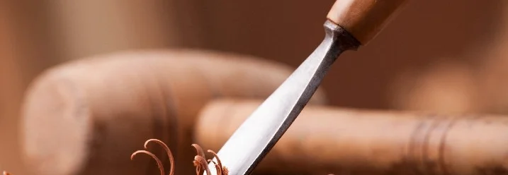 Ein Stechbeitel bearbeitet ein Stück Holz.