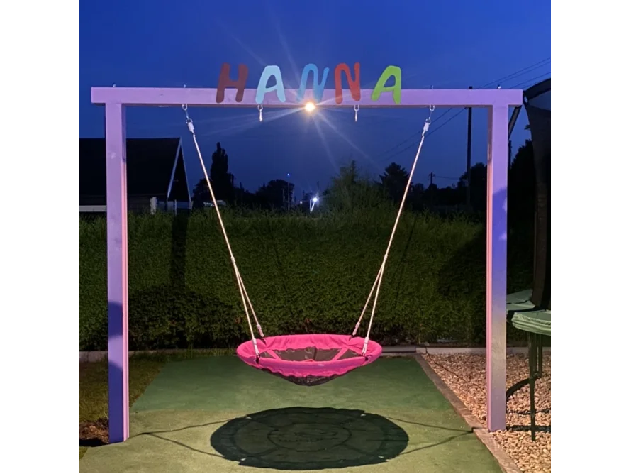 Eine pinke Nestschaukel in einem Garten.