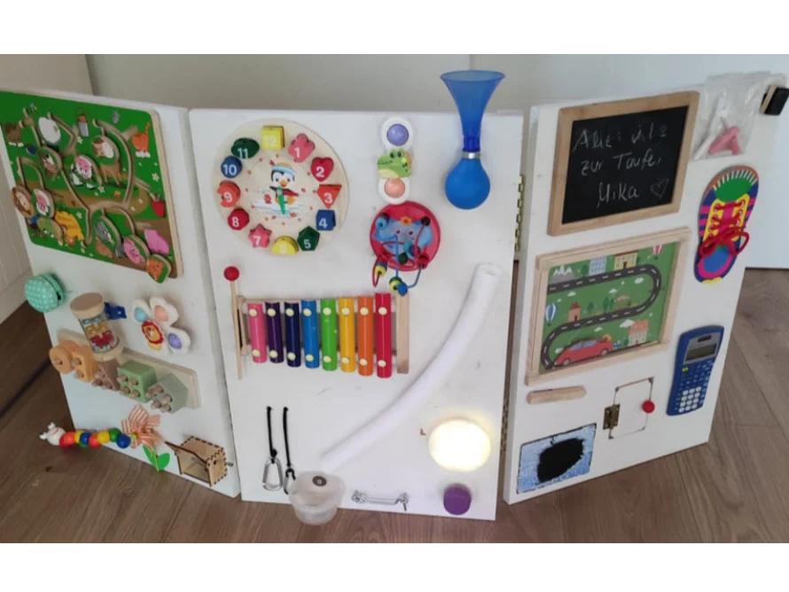 Eine Holzwand mit verschiedenen sensorischen Spielzeugen für Kleinkinder