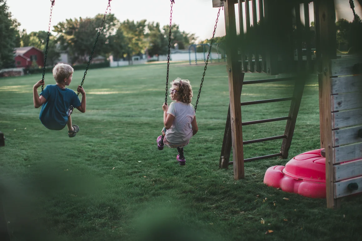 Zwei Kinder schaukeln auf einer Schaukel