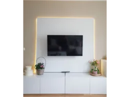 Ein Fernsehgerät an einer weißen Wand mit Beleuchtung.