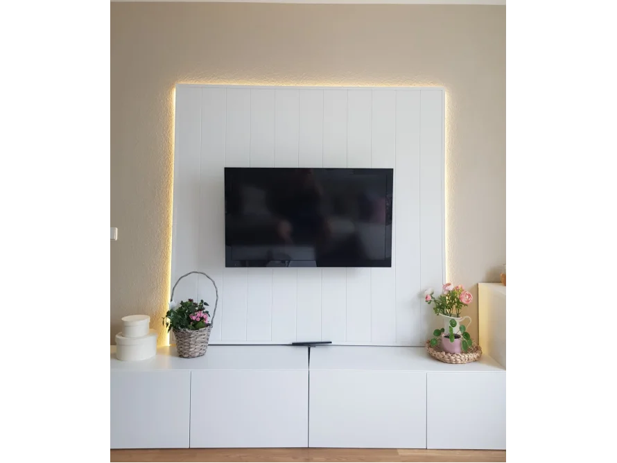 Ein Fernsehgerät an einer weißen Wand mit Beleuchtung.