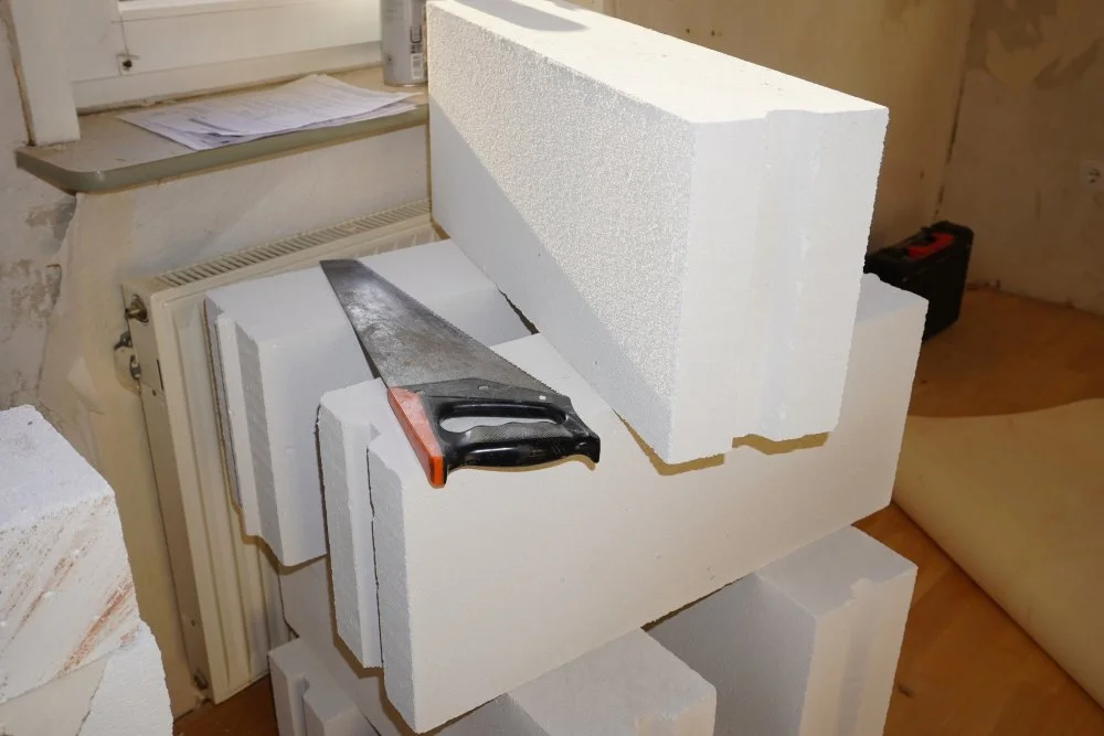 Eine Säge liegt auf gestapelten Ytong Steine.