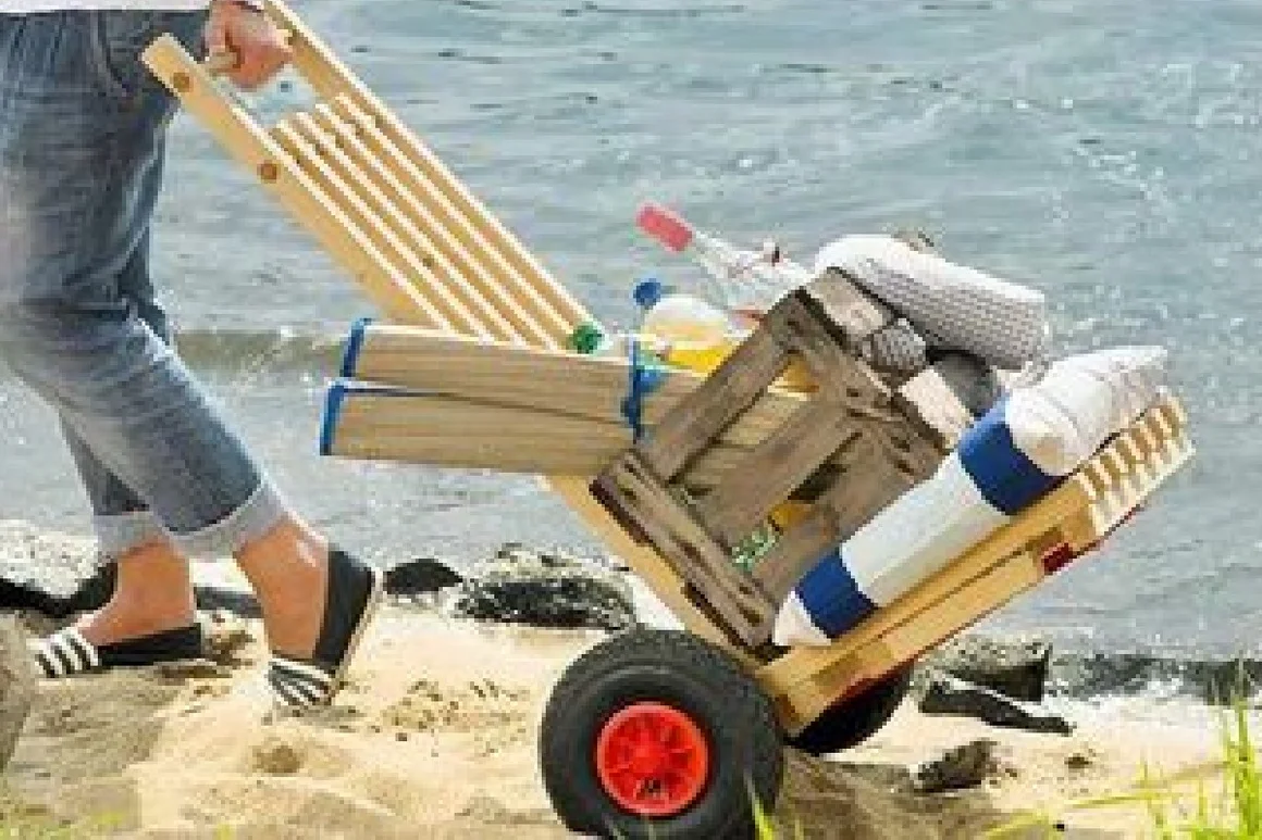 Person zieht Bollerwagen am Strand