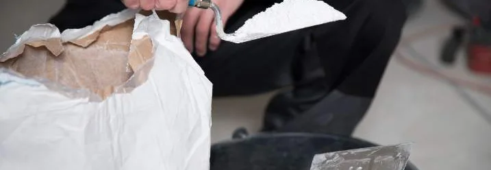 Person nimmt mit Kelle Pulver aus Sack