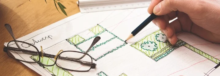 Person zeichnet einen Gartenplan mit Bleistift.