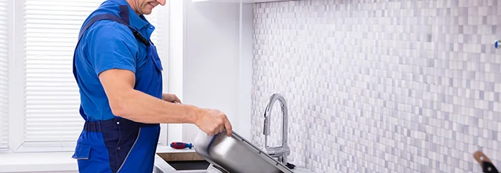 Person baut Spüle in Küche ein